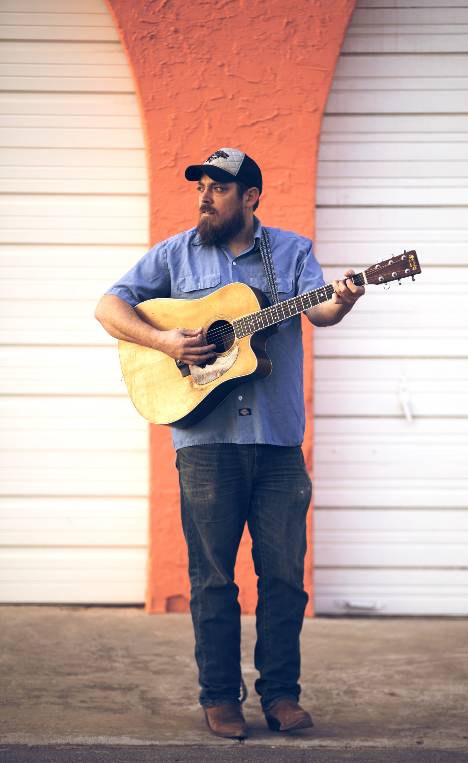 Ben Brock holding his acoustic guitar outdoors